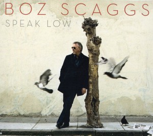 Boz Scaggs' Speak Low cover art: leaning on a short limbless tree with pigeons flying around him.