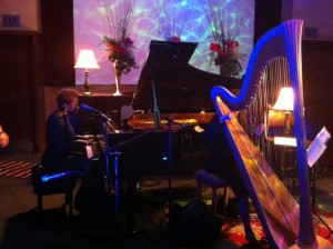 Carol Robbins' harp beside Carmen Lundy singing and playing grand piano.