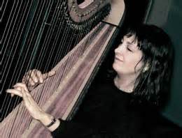 Carol Robbins smiling as she plays her harp.