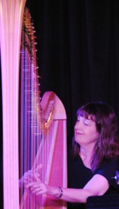 Carol Robbins playing harp with a big smile.