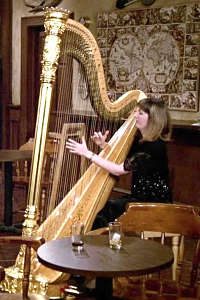 photo of Carol Robbins playing harp on the set of Cheers! TV Show